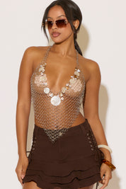 Model is wearing a chainmail top with seashells on a white background
