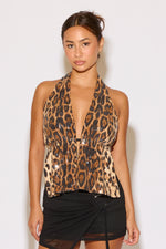 Woman wearing a leopard print halter top against a white background