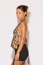 Woman wearing a leopard print top and black shorts against a white background