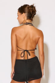 Woman wearing a black halter top and shorts with a plain background