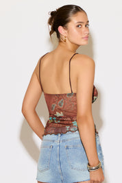 Woman wearing a patterned top and denim skirt against a white background