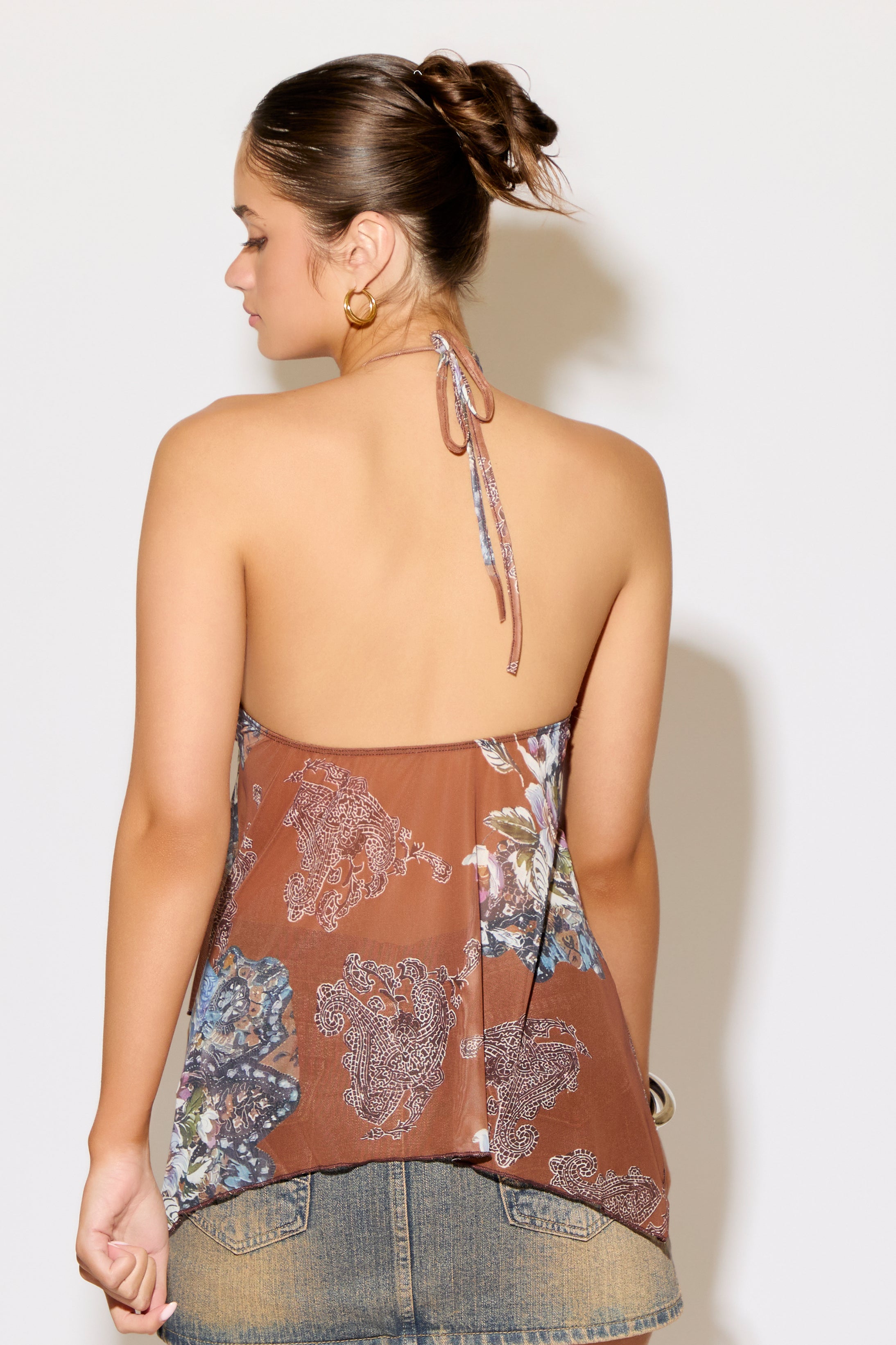 Woman wearing a floral halter top with a plain background