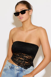 Woman wearing a black lace strapless top and blue jeans against a white background