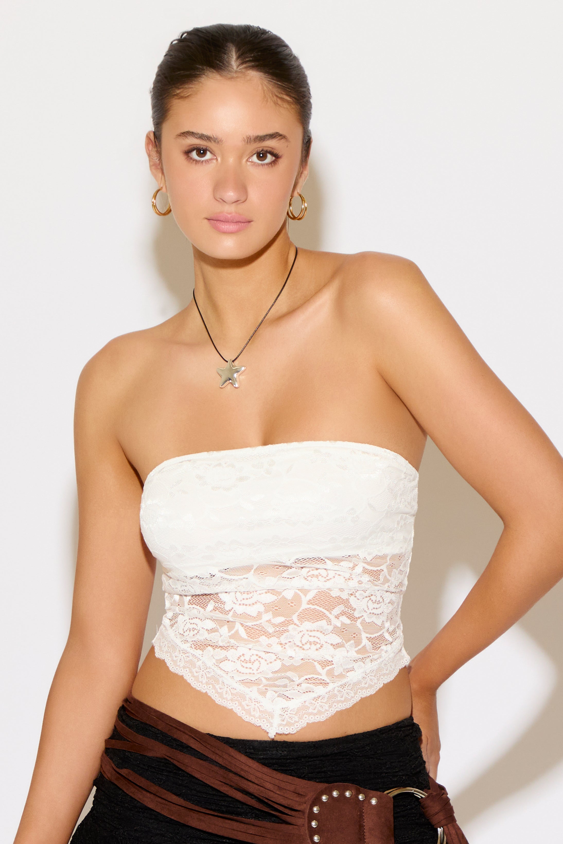 Woman wearing a white lace strapless top with a plain background