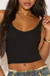 Woman wearing a black crop top and denim shorts against a neutral background