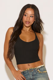 Woman wearing a black tank top and blue jeans against a white background