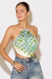 Woman wearing a colorful halter top and jeans against a white background
