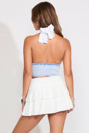 Model is wearing a lace halter bra cup with denim bustier top with a white skirt on a white background.