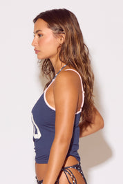 Woman wearing a navy blue tank top with white trim against a plain background