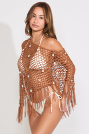 Model is wearing a brown open mesh boat neck poncho on top of a white bikini set on a white background.