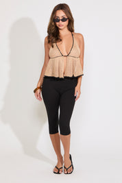 Model is wearing a crochet look contrast edging halter butterfly top with black capris on a white background.