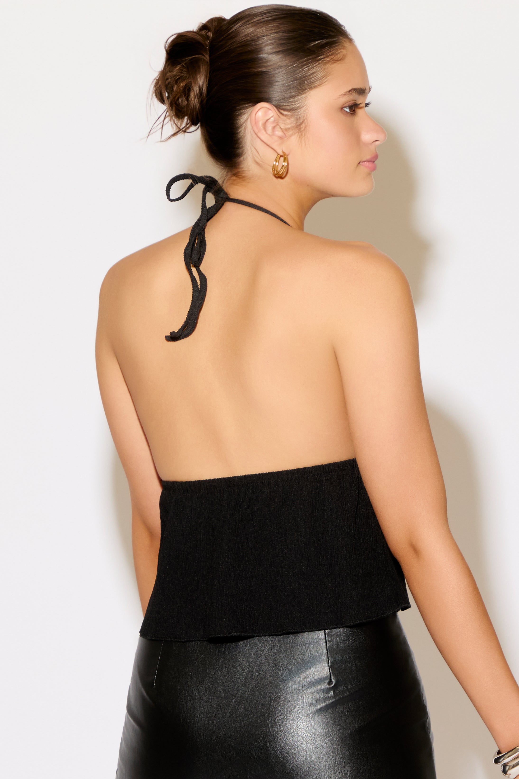 Woman wearing a black halter top with a plain background