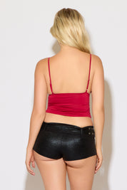 Model is wearing a red deep square v neck ruched bodice cami top with black micro mini shorts on a white background.