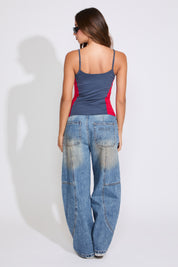 Model is wearing a navy COLOR BLOCK USA & FLAG LOGO SQUARE NECK CAMI TOP with medium denim jeans on a white background. 