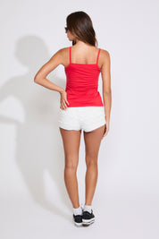 Model is wearing a red London cami top with a denim jacket and white shorts on a white background. 