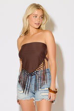 Model is wearing a brown open tie back halter a square neck scarf top with fringe with light denim shorts on a white background.