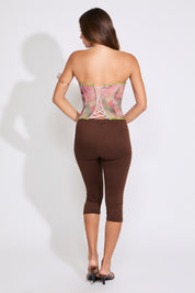 Model is wearing a RUCHED CUP FLORAL MESH CORSET TOP with brown capris on a white background.