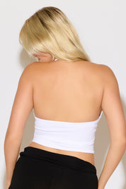 Person wearing a white strapless top against a plain background