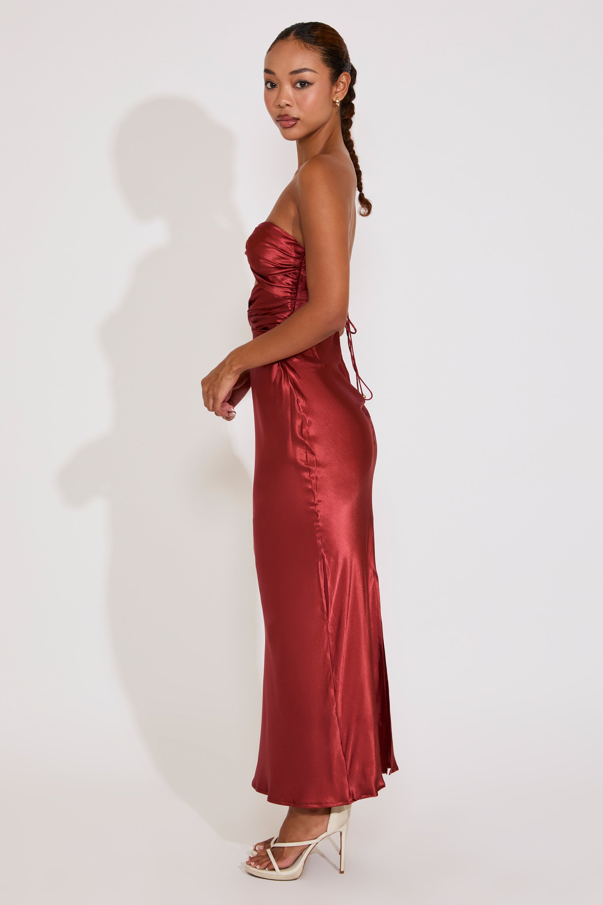 Woman wearing a red satin strapless dress against a white background