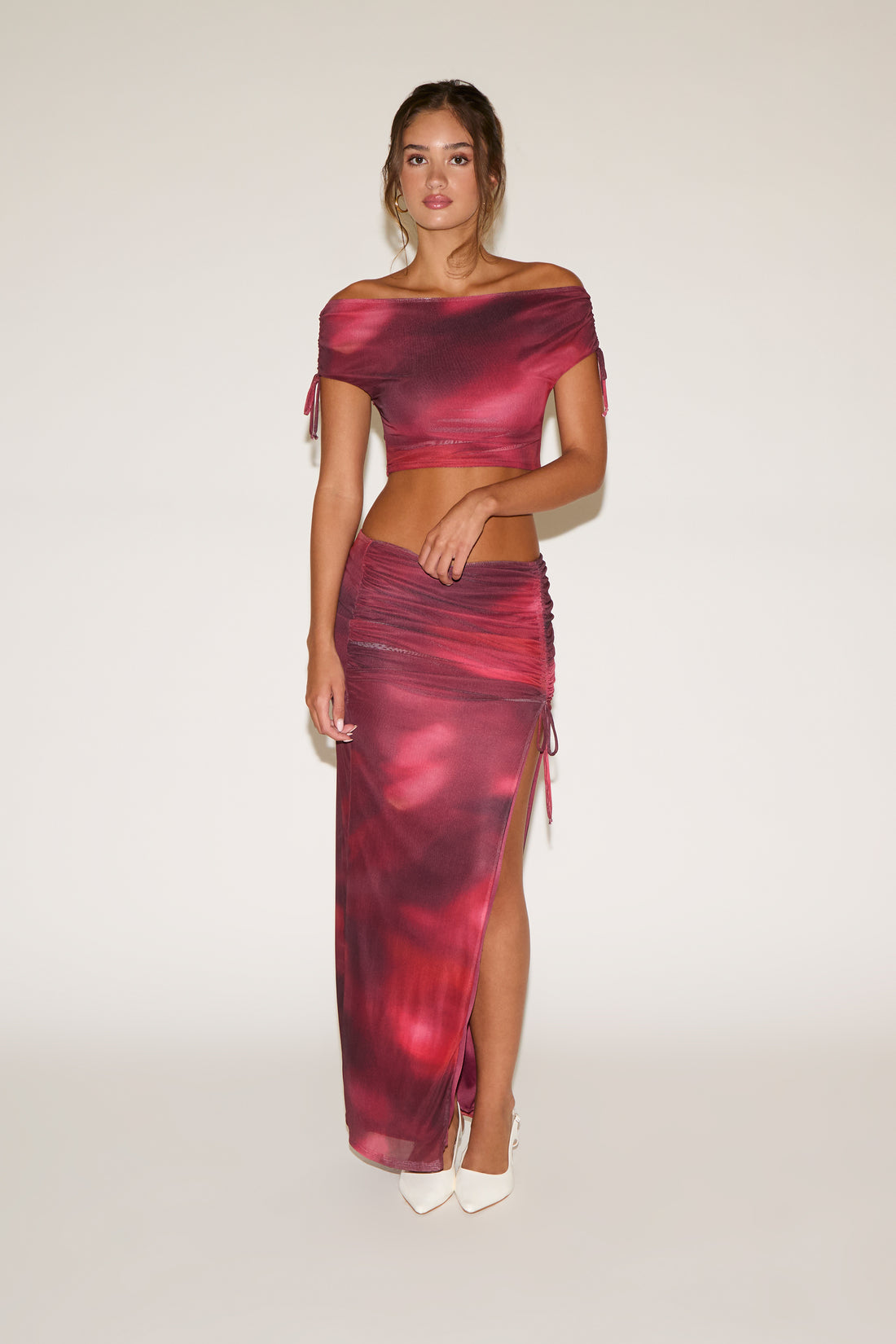 Woman wearing a red and purple off-shoulder top and skirt set on a white background
