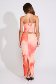 Model is wearing a orange FADED FLORAL TUBE CORSET TOP & MAXI SKIRT SET with brown heels on white background. 