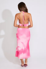 Model is wearing a pink TIE DYE COWL HALTER TOP & MESH MIDI SKIRT SET with pink heels on a white background.