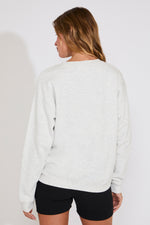 Person wearing a light gray sweatshirt and black shorts on a plain background