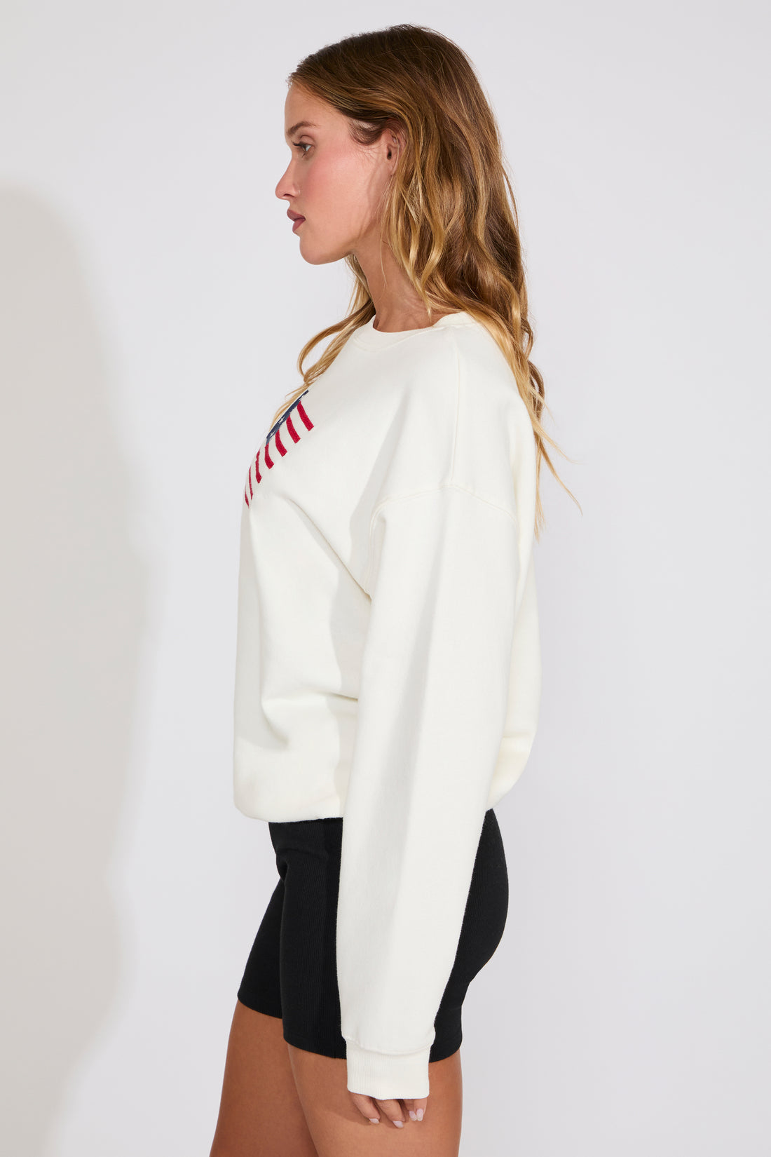 Woman wearing a white sweater with an American flag design on a plain background
