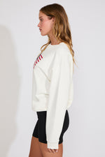 Woman wearing a white sweatshirt with red text on a plain background