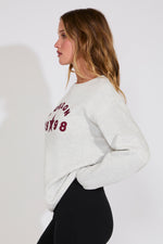 Woman wearing a light gray sweatshirt with text on a white background