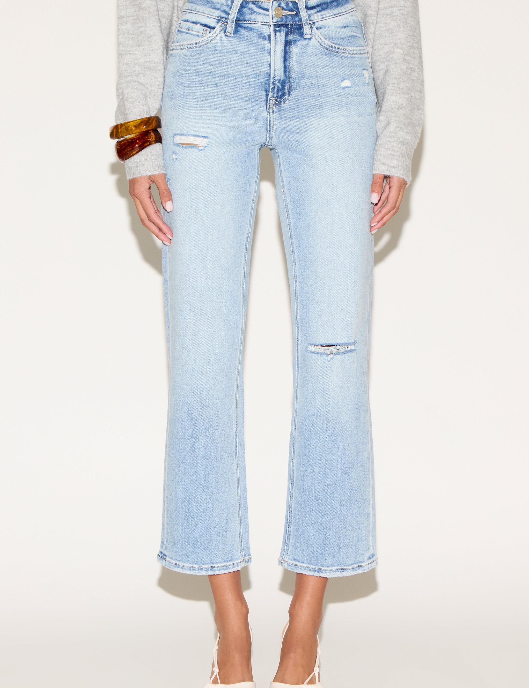 Model wearing light wash cropped straight-leg jeans with subtle distressed details.