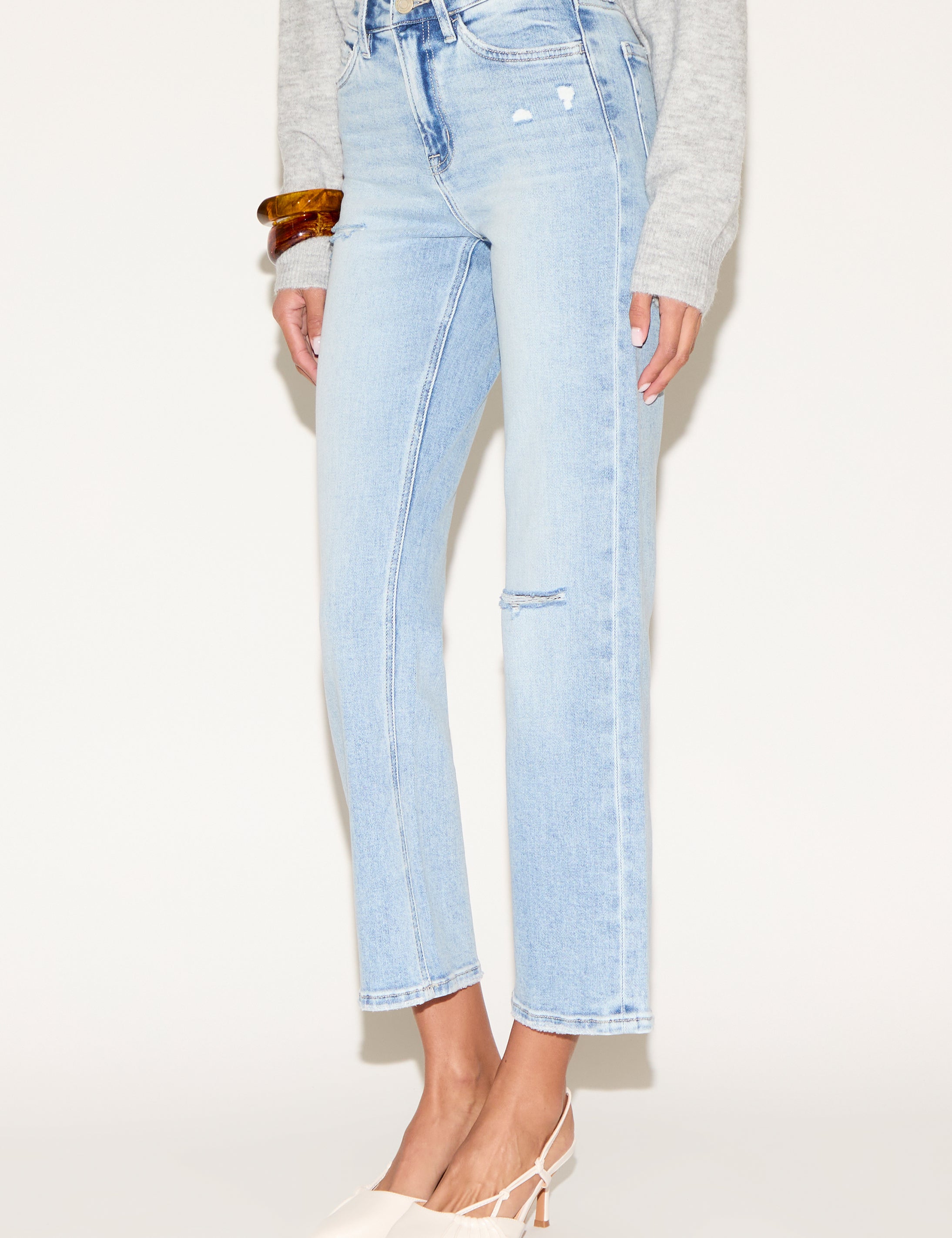 Model wearing light wash cropped straight-leg jeans with subtle distressed details.
