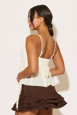 Woman wearing a white top and brown skirt against a plain background