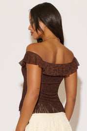 Woman wearing a brown off-shoulder top with ruffled details on a white background
