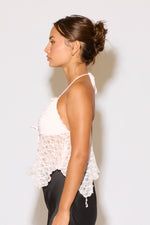 Woman wearing a white lace top against a plain background