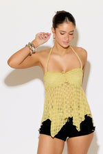Woman wearing a yellow lace top and black shorts against a white background