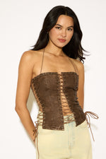 Woman wearing a brown lace-up top against a white background