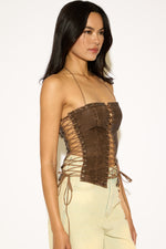 Woman wearing a brown strappy top against a white background