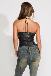 Woman wearing  a black leather corset with denim and  a heart belt. 