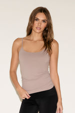 Woman wearing a beige tank top against a plain background