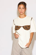 Woman wearing a white t-shirt with a leopard print design on a plain background