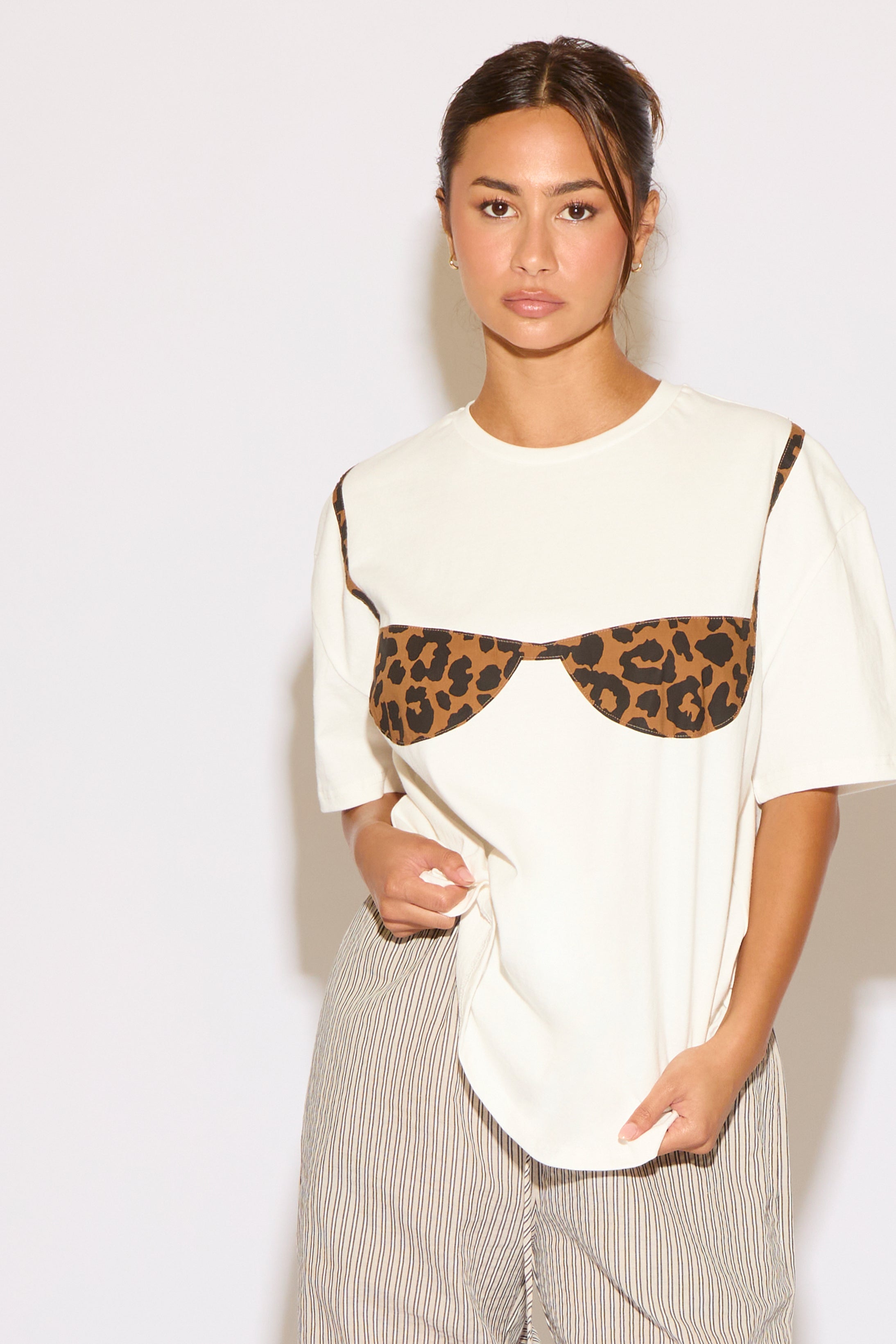 Woman wearing a white t-shirt with a leopard print design on a plain background