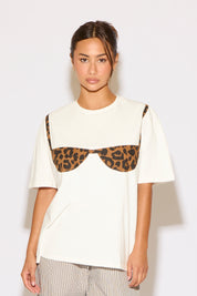 Woman wearing a white t-shirt with leopard print accents on a plain background