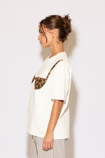 Woman wearing a white t-shirt with a leopard print design on a plain background