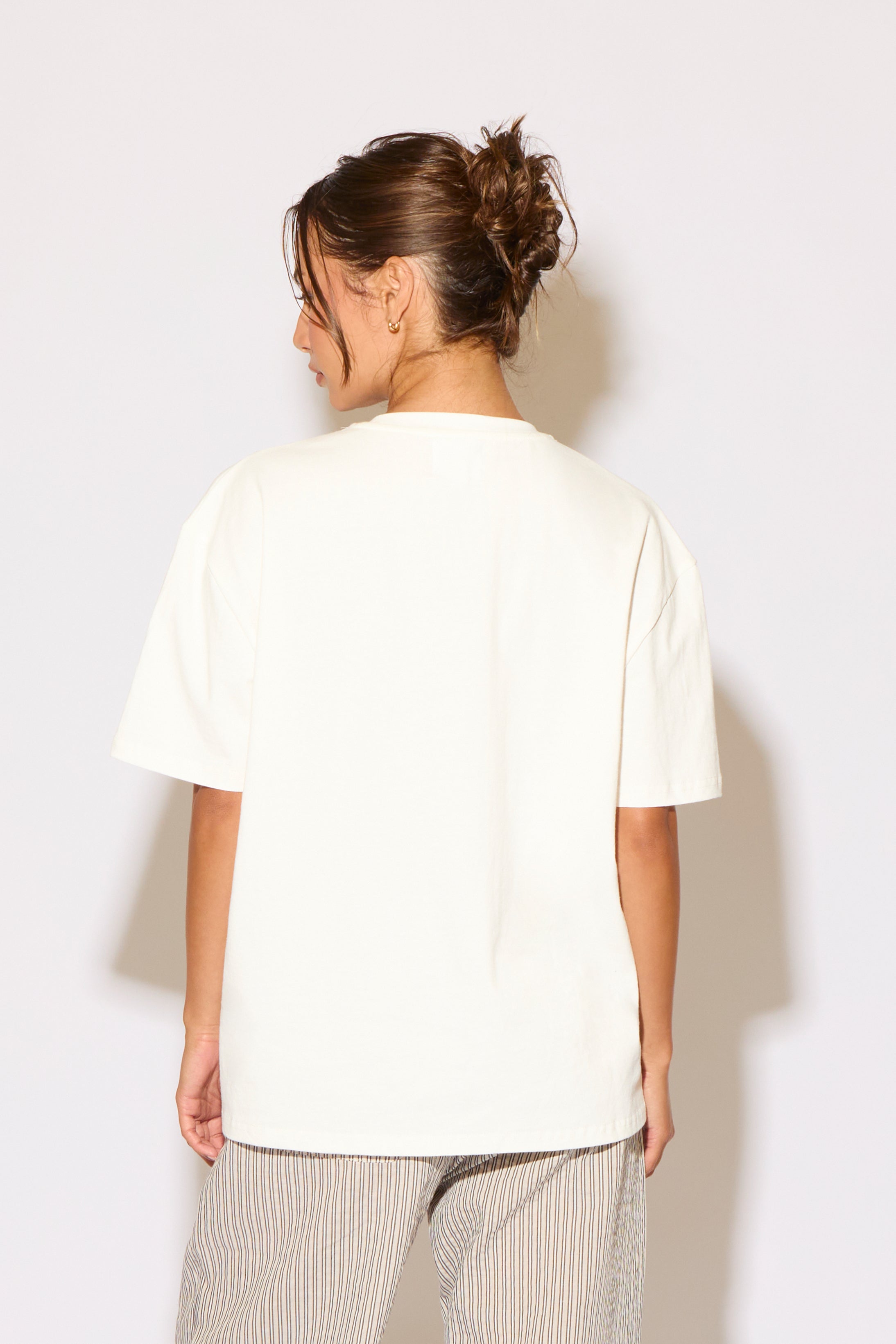 Person wearing a plain white t-shirt against a light background