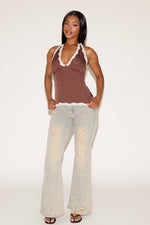 Woman wearing a brown polka dot top and light-colored jeans on a white background