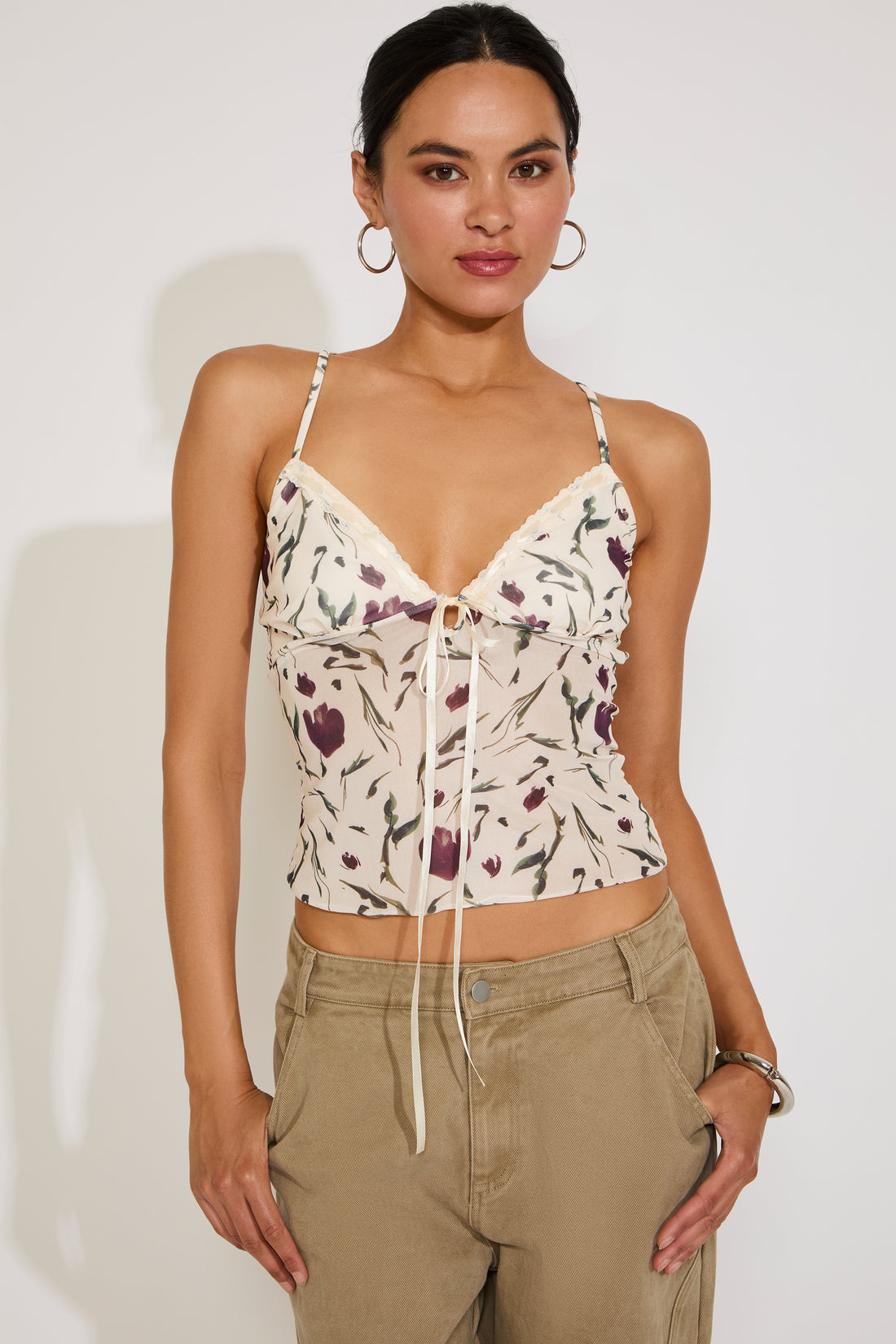 Woman wearing a floral top and beige pants against a white background