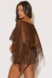 Woman wearing a brown sequined shawl against a white background