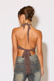 Woman wearing a halter top and jeans against a plain background