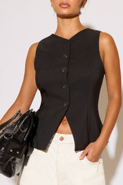 Black sleeveless top with buttons worn by a person, holding a black handbag against a white background